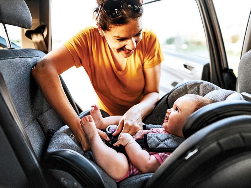 mother buckling baby in a car seat