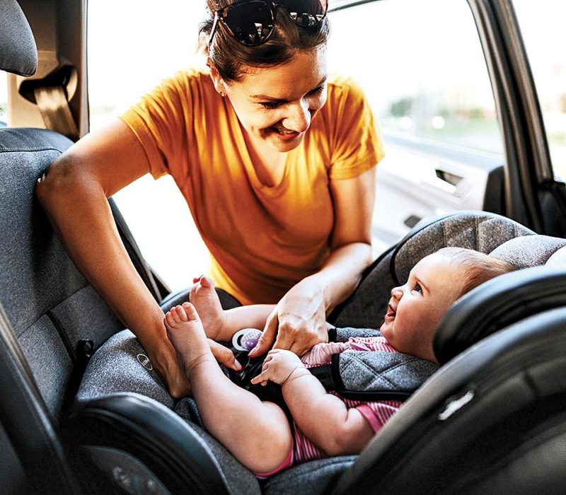 mother buckling baby in a car seat
