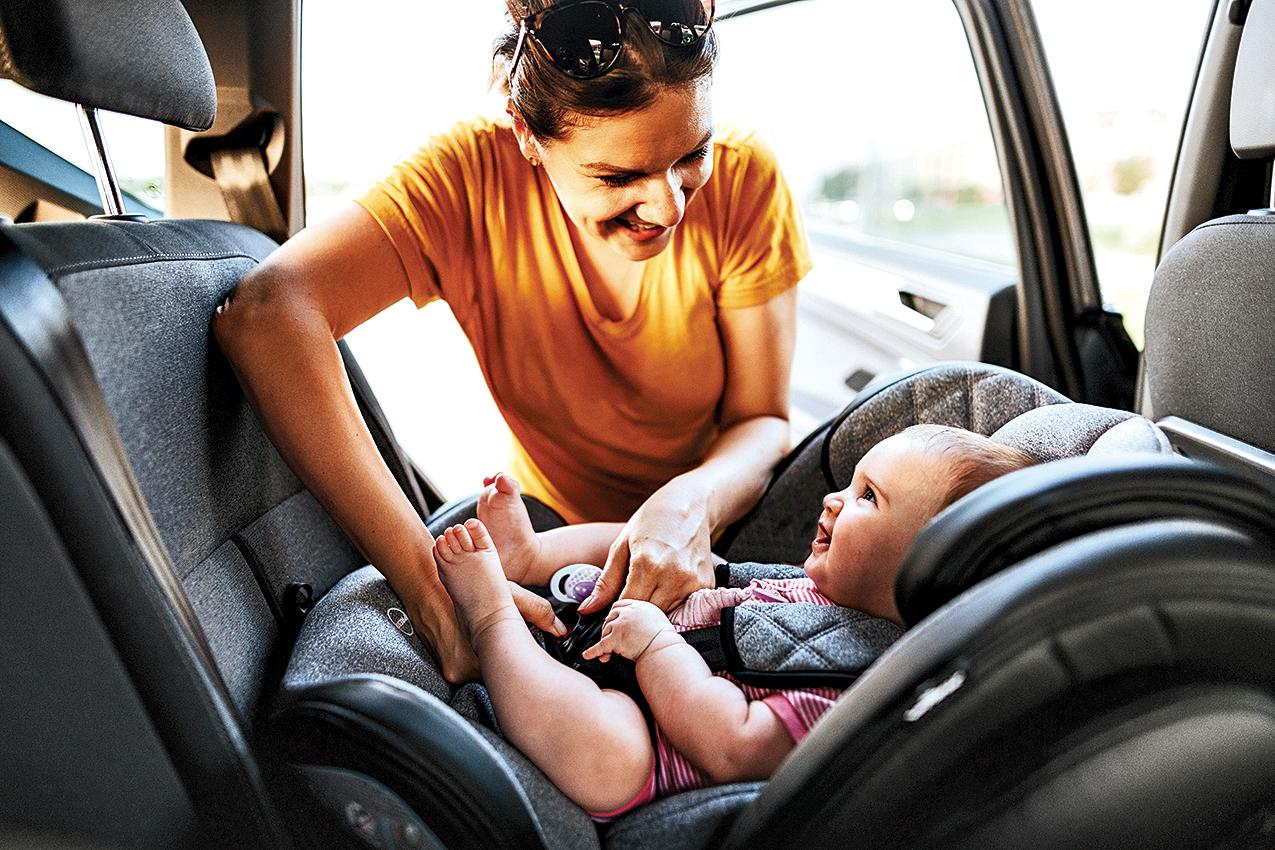mother buckling baby in a car seat