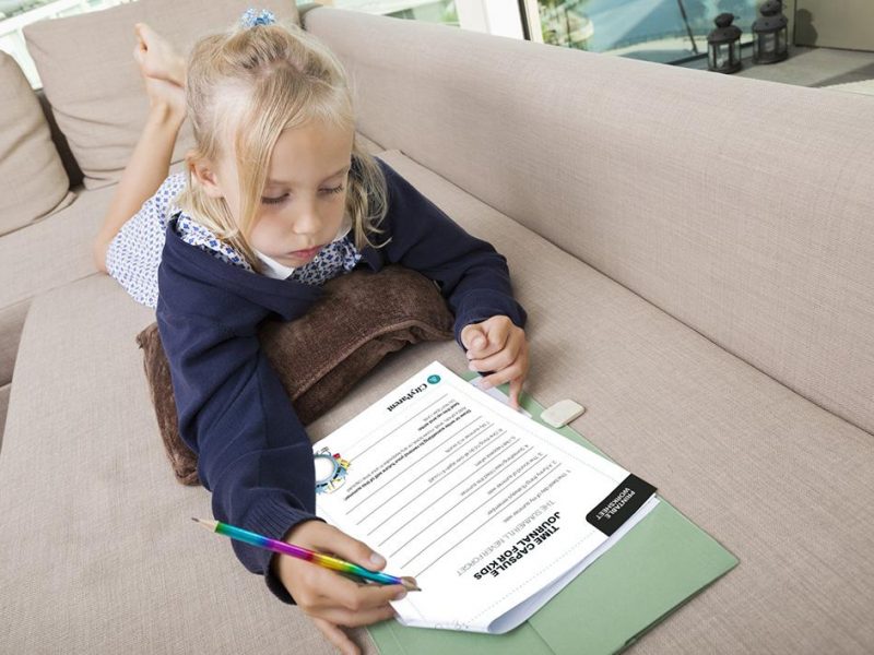 Little girl solving mathematics sums on sofa