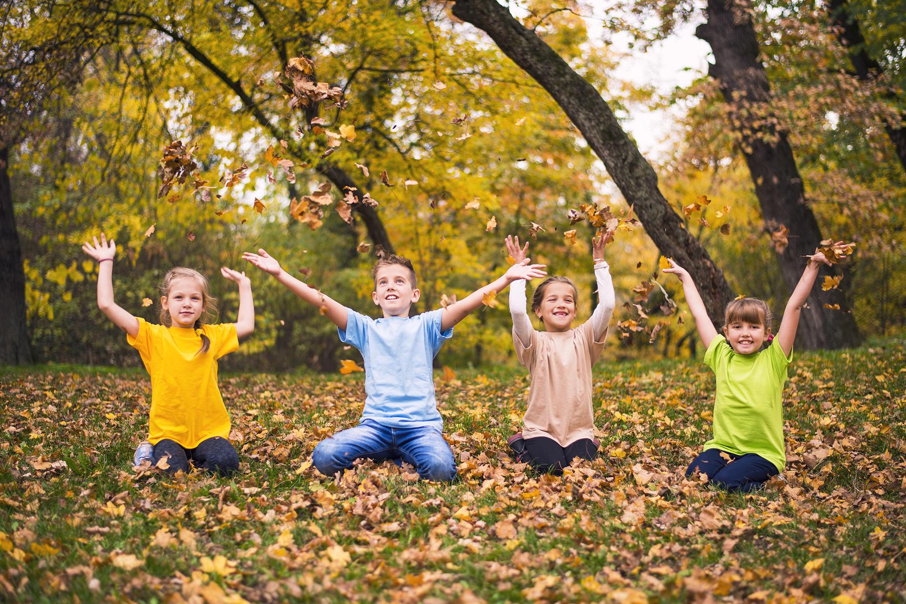 Group of kids throwing autumn leaves