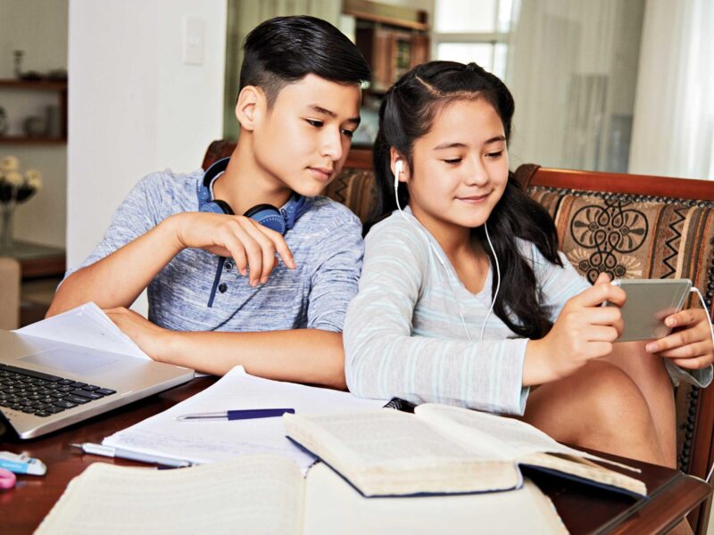 two kids watching on their phone during studying