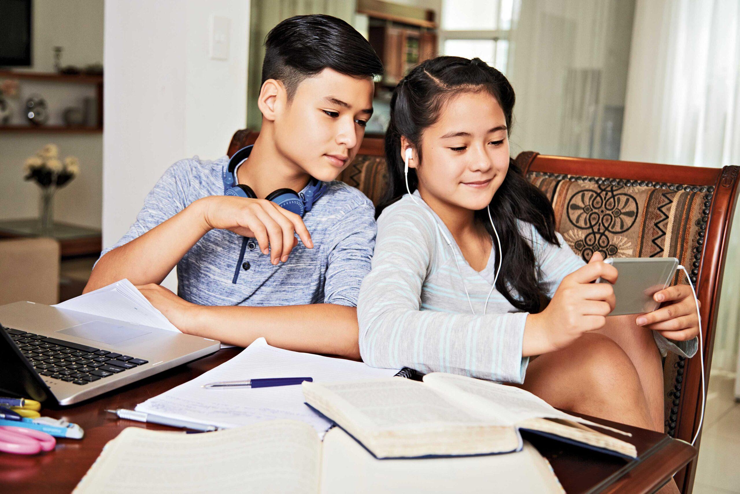 two kids watching on their phone during studying